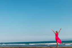 woman wearing pink dress standing on shore
